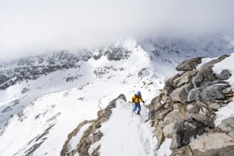 Mountaineers climbing the ridge of Piz Laviner, view of wintry mountain landscape, Grisons Haute