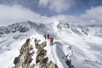 Three mountaineers climbing the narrow ridge of Piz Laviner, view of mountain panorama in winter