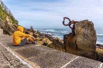 A young man in a yellow sweatshirt visiting the Peine del Viento in San Sebastián. Province of