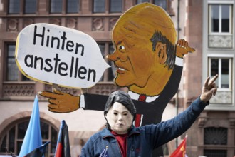 An activist wearing a mask of German Foreign Minister Annalena Baerbock sits on a replica of a tank