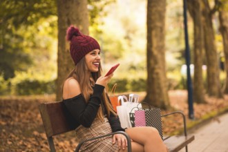 Portrait of a woman in autumn in a forest with brown leaves walking with paper bags after shopping