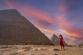 A young girl in a red dress at the pyramid of Cheops the largest pyramid at sunset. The pyramids of