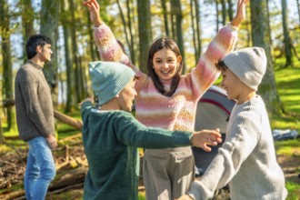 Brothers and sister raising hands after stacking while enjoying a camping day with family in a