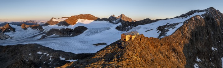 Atmospheric sunrise in a picturesque mountain landscape, alpenglow, aerial view, mountain hut