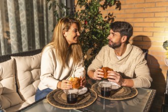 Young couple enjoying a cozy meal and drinks on their balcony, soaking in the warm summer evening
