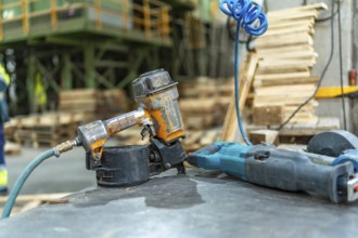 Close-up photo with no people of a compressed air machine gun in a pallet recycling plant workshop
