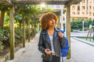 Latin woman enjoying walking along the city using smartphone