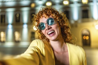 Woman enjoying the city night and taking a selfie standing alone and smiling