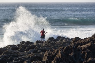 Rocky west coast, black lava coast, coastline, hiker looking at the surf, El Golfo, Yaiza,
