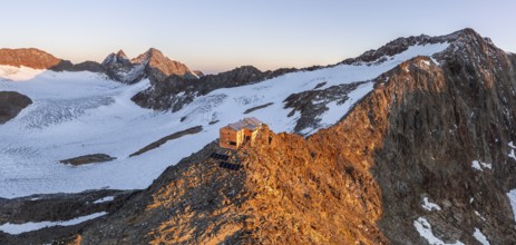 Atmospheric sunrise in a picturesque mountain landscape, alpenglow, aerial view, mountain hut