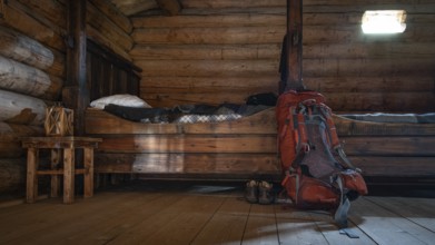 Rustic interior of a wooden hut with small beds and a rucksack and hiking boots, Olavsweg or