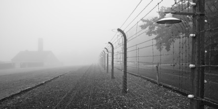 Reconstructed camp fence with crematorium in the fog at beech forest concentration camp, now a