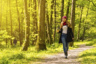 Latin girl with a black jacket, scarf and red woolen hat enjoying in an autumn park, walking along