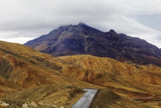 A winding road leads through a mountainous landscape under a cloudy sky, Pajara, Fuerteventura,