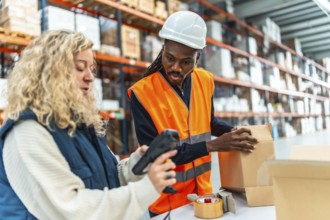 Two multi-ethnic warehouse workers scanning boxes to deliver in a distribution warehouse