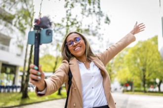 Happy stylish latin woman vlogger exploring a city while recording online video