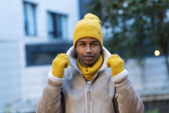 Stylish man wearing a bright yellow hat, gloves, and scarf, braving the cold winter weather while