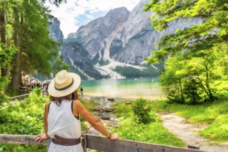 Tourist enjoying breathtaking view of lake braies, surrounded by majestic mountains and lush