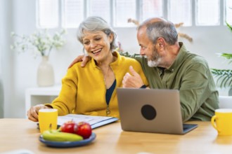 Senior man congratulating his wife for an announcement that she received online
