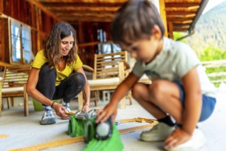 Mother and son enjoying quality time together, building toy train tracks on a porch
