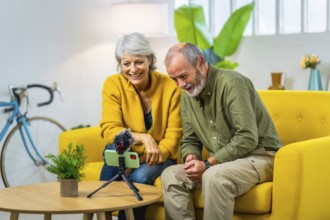 Senior couple doing an online video with family using mobile phone attached to a tripod and mic