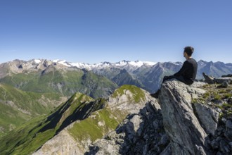 Mountaineer sitting on a rock in front of a mountain panorama with Großvenediger, mountain