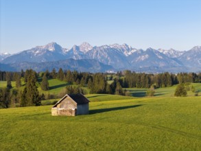 Small hut on a green meadow with an impressive mountain panorama in the background, Alps, near