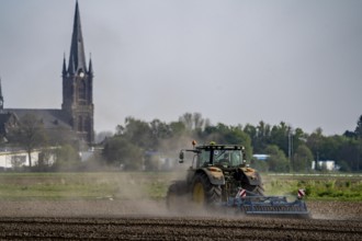 A tractor works a field, due to long dryness in spring, no rain for more than 4 weeks, the fields