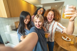 Group of cheerful young multi ethnic friends taking selfie while drinking juice and smiling in
