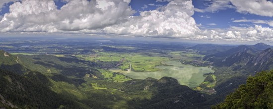Panoramic view from Herzogstand down to a mountain landscape with Lake Kochel and cloudy sky,
