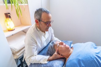 Mature male therapist doing an oriental neck massage to a mature woman in a clinic