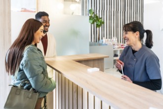 Happy couple engaging with a friendly receptionist in a bright, modern dental clinic, enjoying a