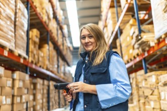 Portrait of a happy blonde female warehouse worker smiling at camera while standing doing inventory