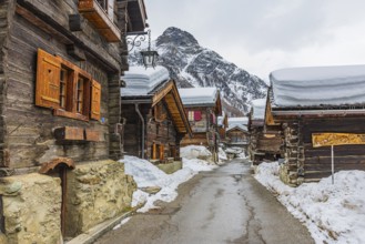 Street with historic old snow-covered wooden houses, mountain village of Zinal, Val d'Anniviers,