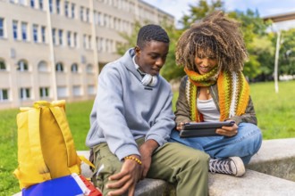 Multiracial friends sharing digital tablet outside university campus
