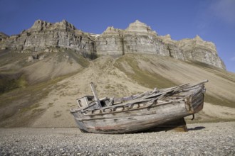 Wooden wrecked fishing boat stranded on shingle beach of Skansbukta, Svalbard, Spitsbergen