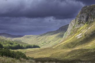 Mountain scenery showing dark rain clouds rolling in over sunny hillside and valley in Wester Ross,