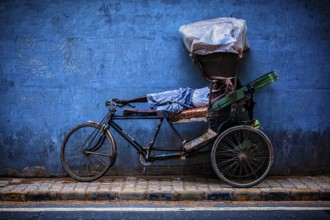 DELHI, INDIA, SEPTEMBER 11, 2011: Indian cycle rickshaw driver sleeping on his bicycle in the