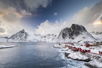 Rorbuer cabins of Hamnoy by the fjord, snowy mountains in the back, Hamnøy, Reine, Moskenesøya,