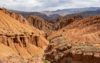 Eroded mountain landscape with sandstone cliffs, canyon with red and orange rock formations,