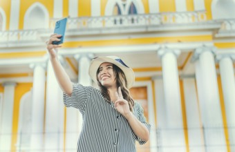 Young tourist woman with hat taking selfie in a square. Selfies and vacation concept. Beautiful