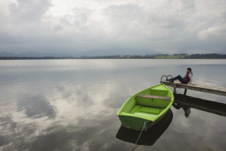 Woman 50-55, wooden jetty, green rowing boat, Hopfensee, Hopfen am See, near Füssen, Ostallgäu,