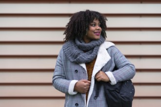 Portrait of black ethnic girl a gray wall in the university, with a schoolgirl on the back of the