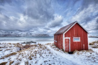 High Dynamic Range (HDR) image of red rorbu house shed on beach of fjord. Skagsanden beach, Lofoten
