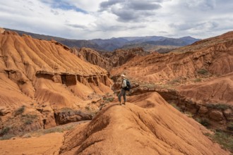 Mountaineer on a mountain ridge, view of eroded mountain landscape with sandstone cliffs, canyon
