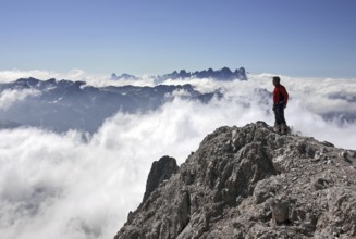 Mountaineer looking from the Cima Scalieret over blanket of clouds and mountain peaks of the