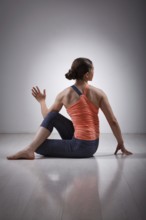 Beautiful sporty fit yogini woman practices yoga asana ardha matsyendrasana, half spinal twist pose