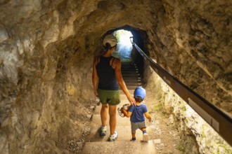Mother and son walking up the stairs in a tunnel carved into the rock face at tolmin gorge in