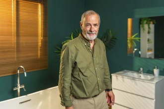 Portrait of a caucasian senior man standing in the bathroom at home smiling at camera