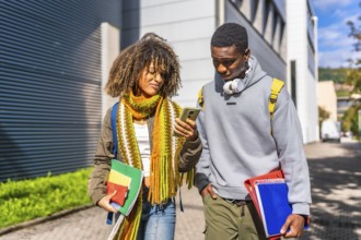 Multi-ethnic students checking information with the mobile phone walking along the university